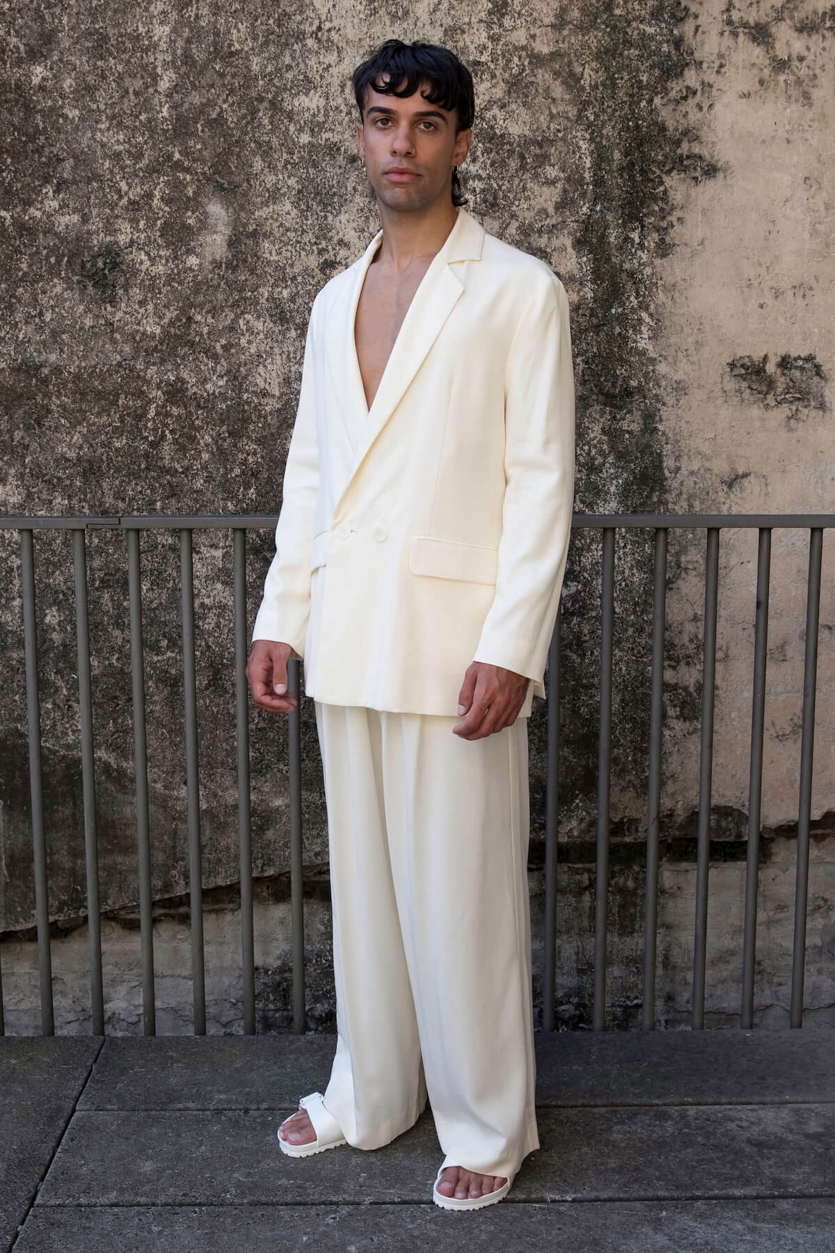 The Glade model wears a men’s double breasted blazer and mens high waisted pants in white