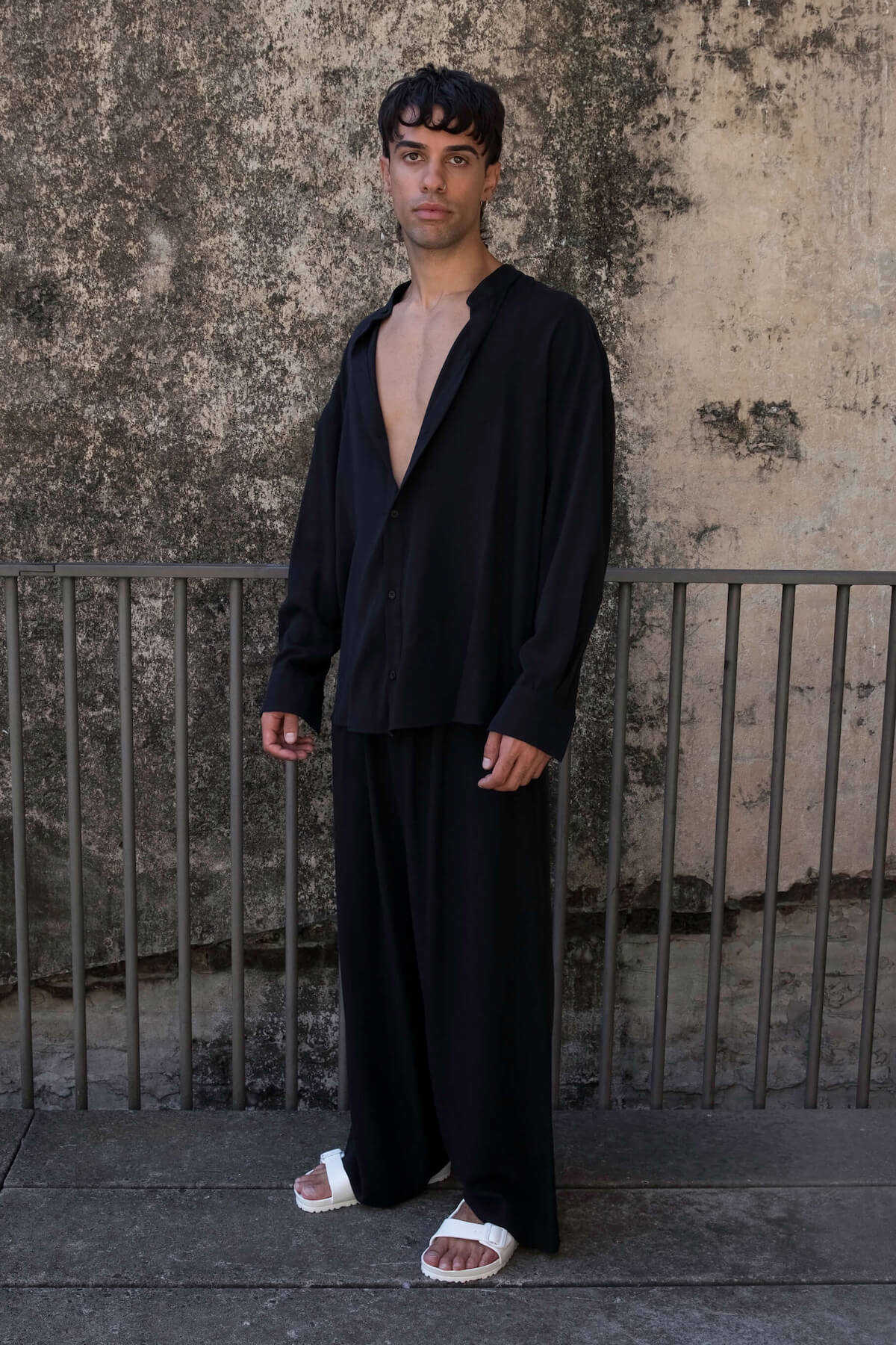The Glade model wears men's high waisted pants and oversized shirt in black